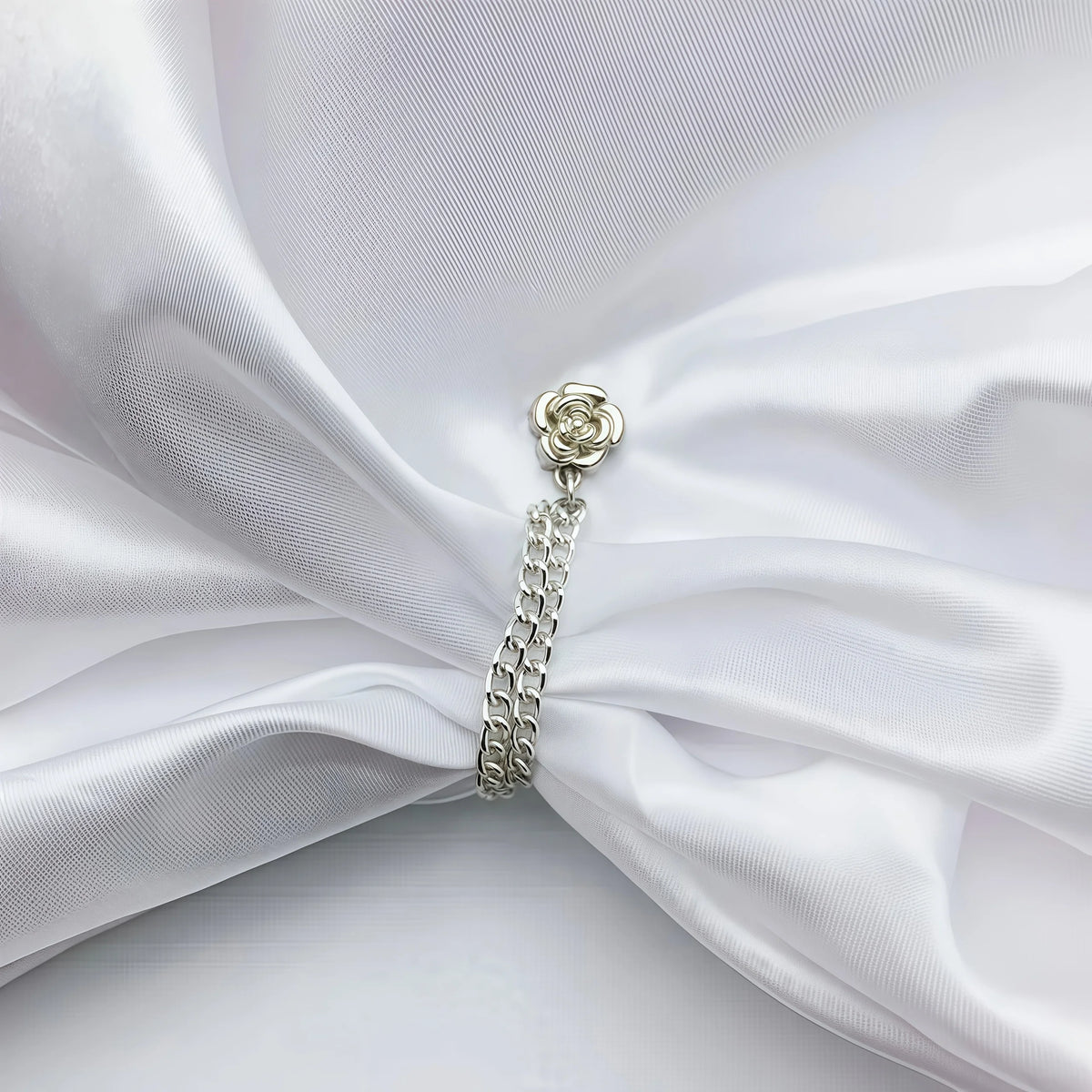 Silver magnetic chain buckle with a floral charm worn on white satin fabric.