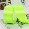 A roll of bright lime green satin ribbon is shown next to a green card with foliage design.