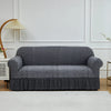 A charcoal gray jacquard stretch sofa cover displayed on a white sofa against a light wall.