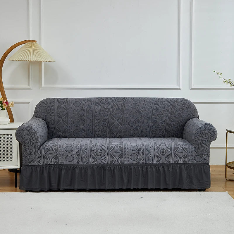 A charcoal gray jacquard stretch sofa cover displayed on a white sofa against a light wall.