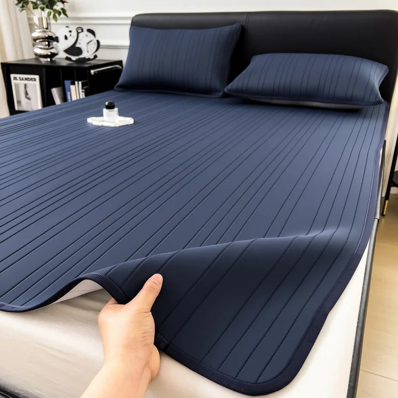A dark blue cooling ice silk bed pad is shown being touched on a white surface.