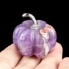 A handcrafted natural stone pumpkin figurine with purple and white coloration is held in a hand.