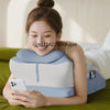 A woman is using a large memory foam body pillow for comfort while relaxing on a green couch.