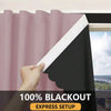 A hand is pulling a black blackout window curtain across a window frame.