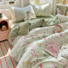 A light green and pink floral duvet cover set with matching pillowcases displayed on a bed.