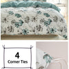 A white duvet cover featuring a watercolor floral pattern in teal and grey, shown on a bed.