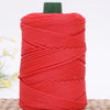 A spool of bright red crochet ice rope with a dark green cap, lying on a woven surface.
