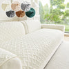 A white quilted sofa cushion displayed on a light-colored sofa with various colored fabric swatches.