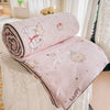 A pink quilted blanket with a white bear design and happy text is rolled up on a white surface.