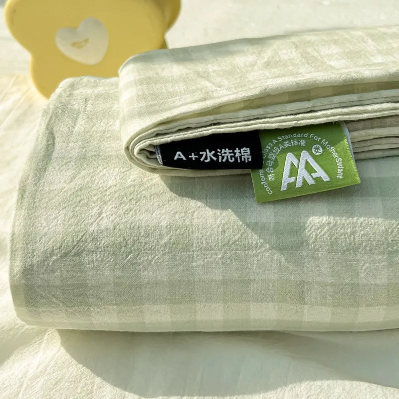 A folded light green organic cotton flat sheet and pillowcases with a tag indicating A+ water washing standards.