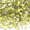 A pile of clear glass rhinestones in various shades of yellow and green for DIY crafts