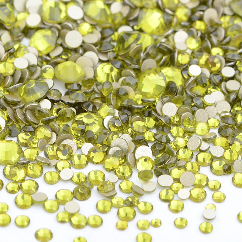 A pile of clear glass rhinestones in various shades of yellow and green for DIY crafts