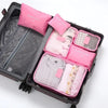 A black travel packing cube set with six pink and white pouches is displayed in an open suitcase.