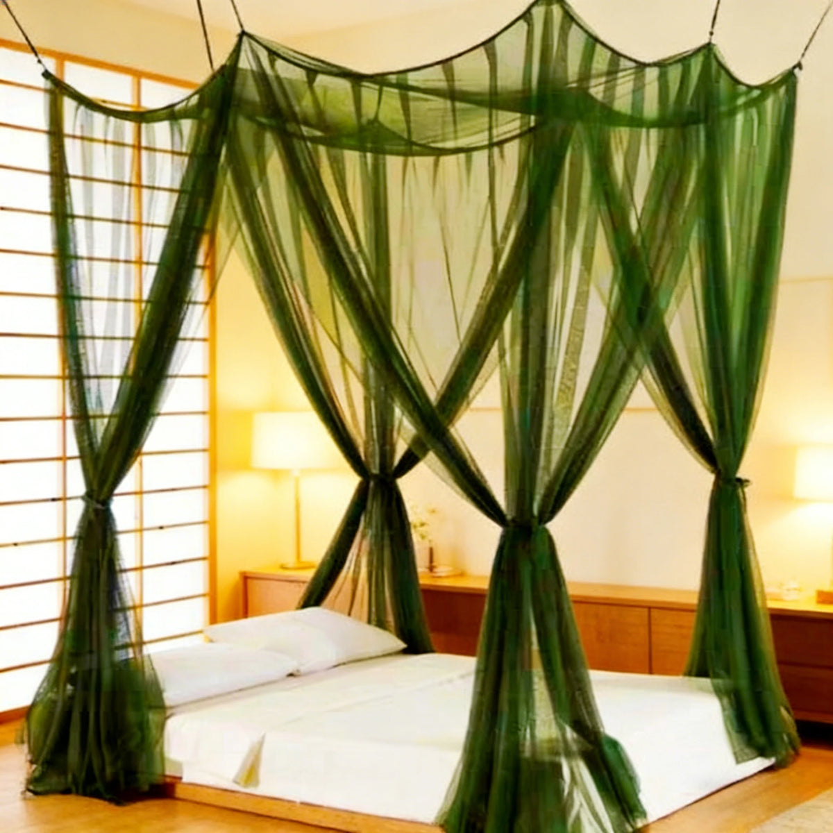 A square mosquito net bed canopy in green fabric draped over a bed in a bright room.