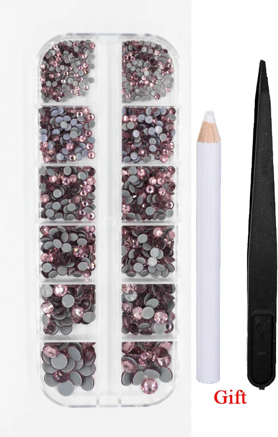 A clear plastic case containing various shades of pink and gray crystal rhinestones and an applicator tool for crafting