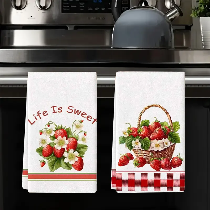 A set of two white kitchen towels featuring a red strawberry floral design on the fabric.