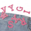 Pink pearl rhinestone letter patches spelling WY and WSD on a denim fabric