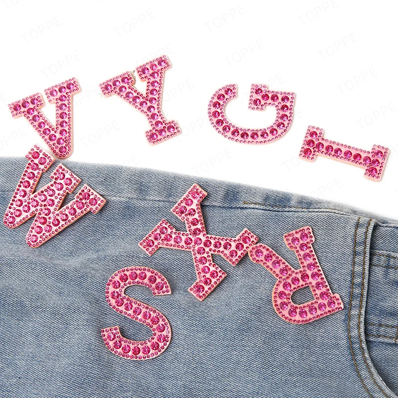 Pink pearl rhinestone letter patches spelling WY and WSD on a denim fabric