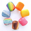 A collection of hand knitting yarn in various shades and gradients, arranged in a circle.