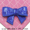 A royal blue sequin bow patch for DIY decoration shown on a pink grid background.