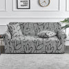 A gray elastic sofa cover protector featuring a black floral print on a sofa.