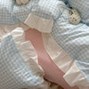 A light blue and white checkered duvet cover set with ruffled white pillowcases and a pearl decorative item.