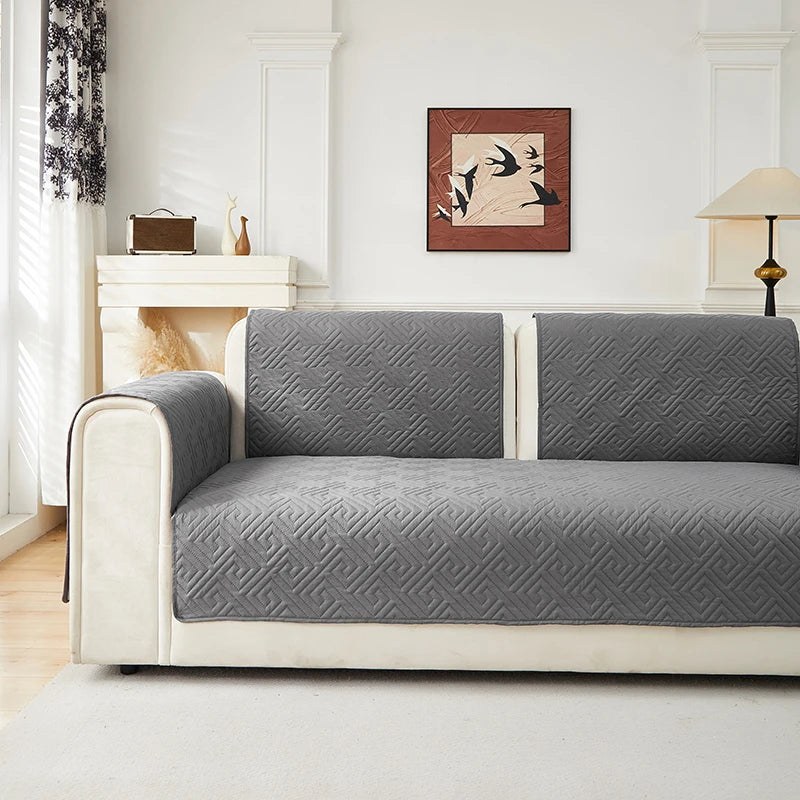 A light gray geometric quilted sofa cushion cover on a white wooden bench in a bright room.