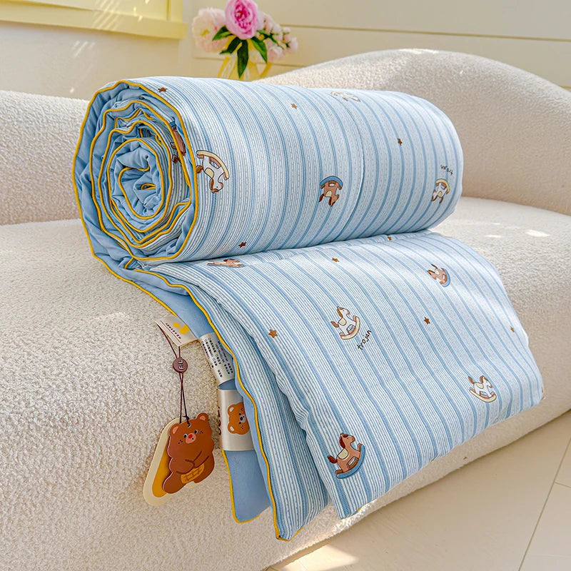 Light blue striped quilt with cartoon animal patterns resting on a white sofa.