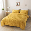 A yellow quilted bedspread and pillows on a bed in a bright room.