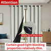 Two panels of light gray blackout curtains hanging on a rod, demonstrating the fabric thickness.