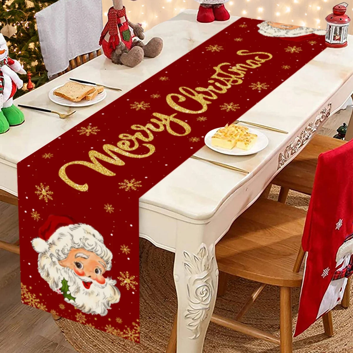 A festive red table runner with gold lettering and Christmas designs is displayed on a white marble table.