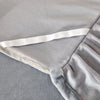 A close-up of a thick milk velvet bed skirt with a white tie detail, shown in a soft gray fabric.