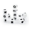 A collection of white soft silicone alphabet beads arranged in vertical stacks and scattered on a white surface.