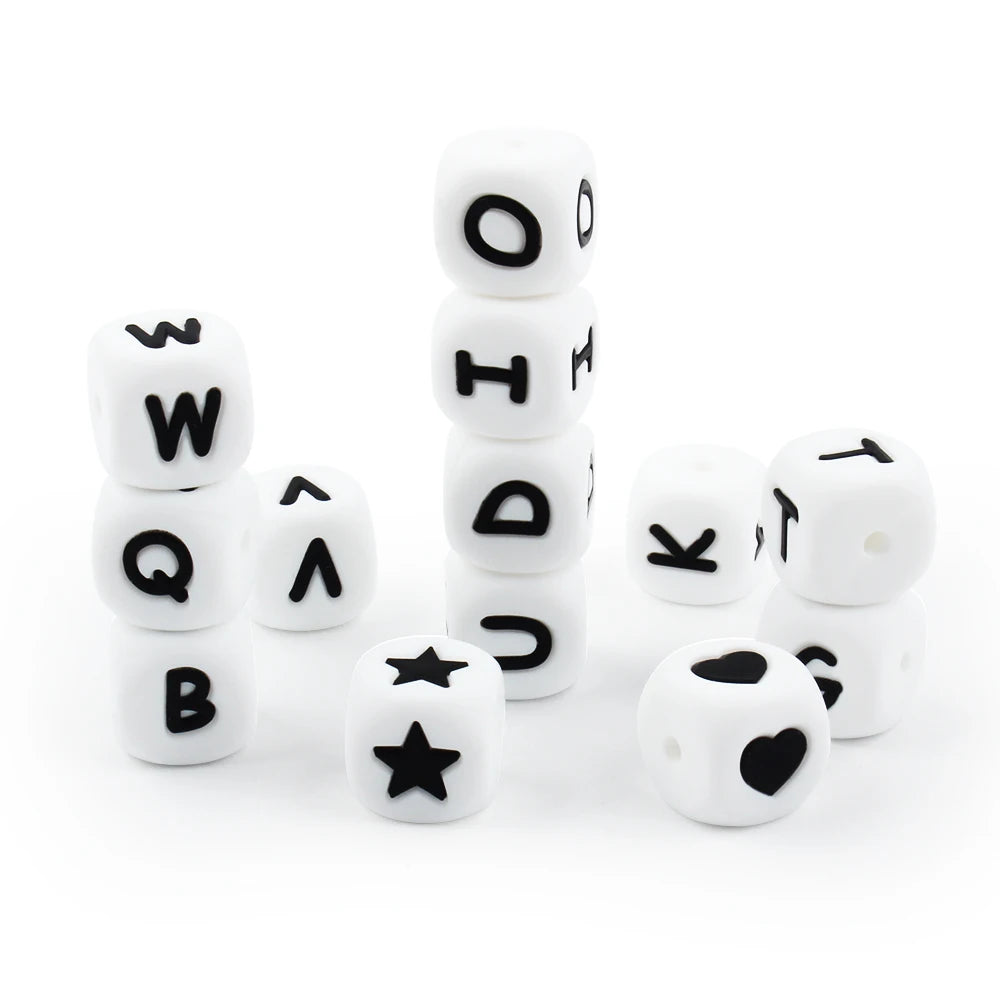 A collection of white soft silicone alphabet beads arranged in vertical stacks and scattered on a white surface.