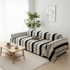 A bohemian striped sofa cover draped over a light-colored sofa in a bright room.