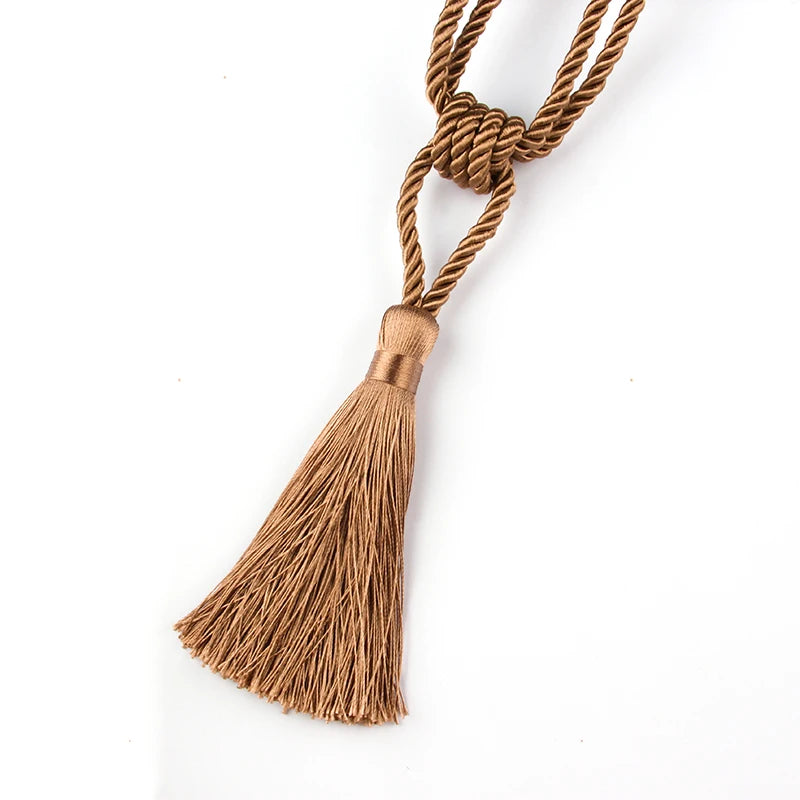 A bundle of golden brown rope tied into a decorative tassel for curtain tiebacks.