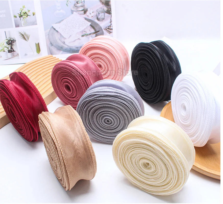 Rolls of silky organza ribbon in various colors including pink, red, gray, black, and cream for crafting