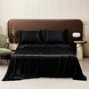 A black satin flat bed sheet set is displayed on a bed with brown upholstery and pillows.