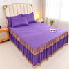 Purple luxury floral bed skirt protecting a mattress with a padded headboard and white curtains.