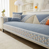 A blue quilted sofa cover with lace trim and geometric pattern displayed on a modern sofa.