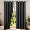 A pair of black blackout thermal curtains hanging in a doorway, with a view of a garden outside.