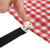 A hand is holding a black strap attached to a red and white checkered bed sheet with silver clips.