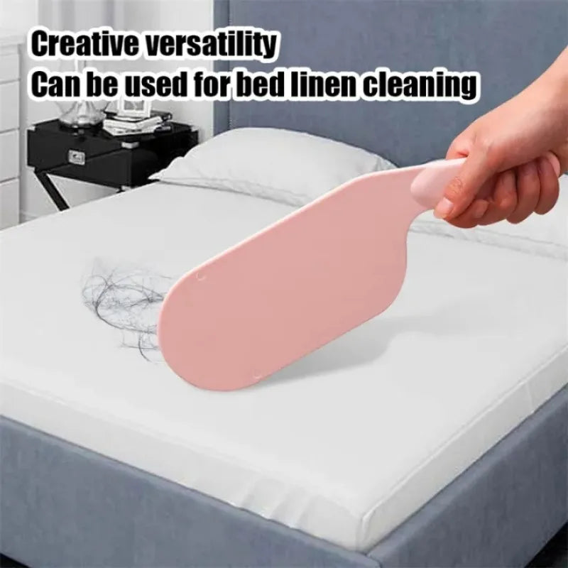 A hand is using a pink bed sheet folding and organizing tool on a white bed linen.