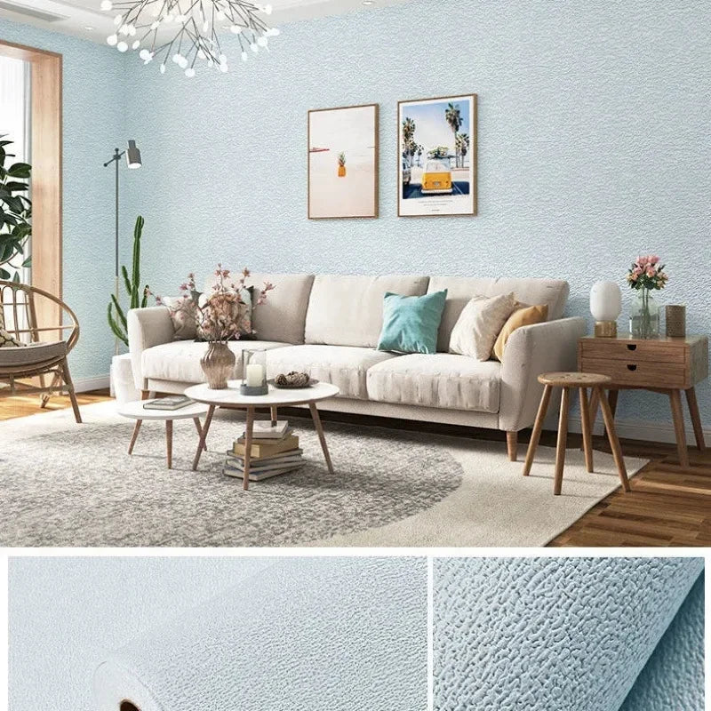 A living room featuring a light blue textured wall, a beige sofa, and framed artwork.