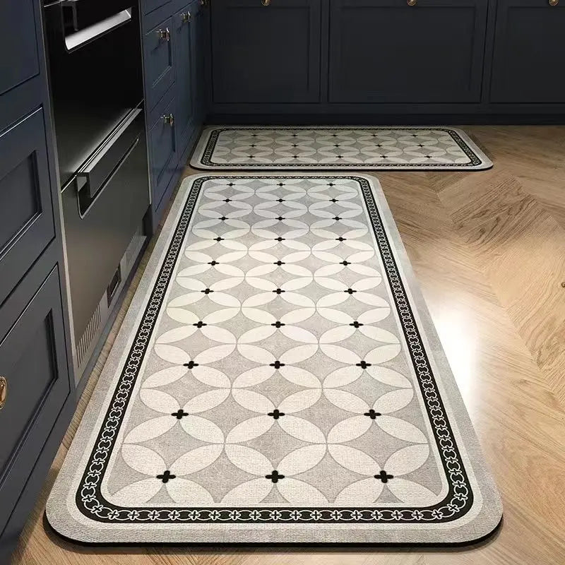 A rectangular gray and black anti-slip floor mat placed on a light wood floor in a kitchen or entrance area.