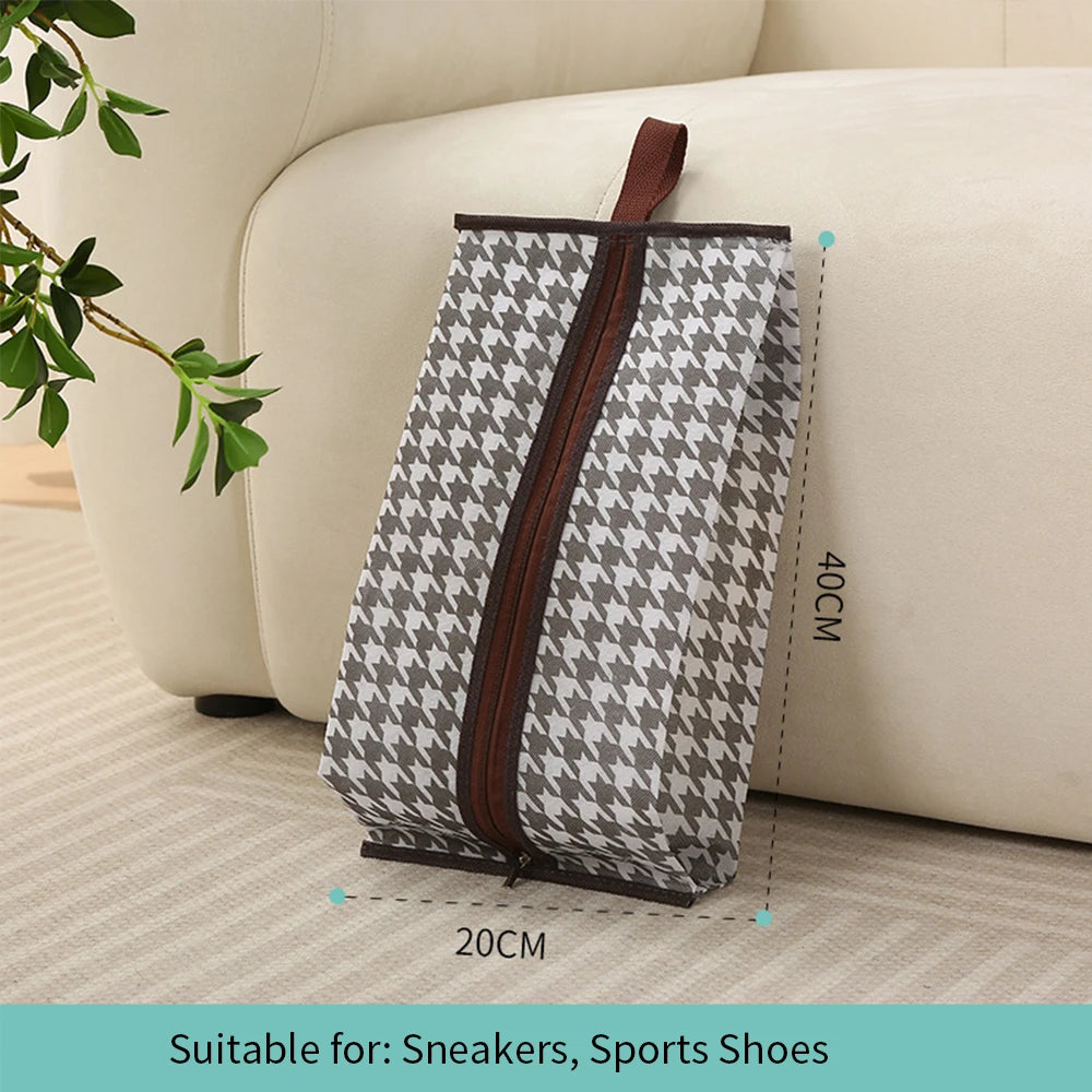 A gray and white patterned portable boot storage bag with a brown carry handle resting on a light-colored sofa.
