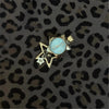 A silver star-shaped pocket watch keychain with a light blue face and hands is displayed on a leopard print background.