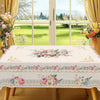 Vintage pink rose sunflower floral tablecloth displayed on a wooden table near a large window.