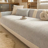 A light beige striped chenille sofa cover with neutral accent pillows and a small teacup on the fabric.