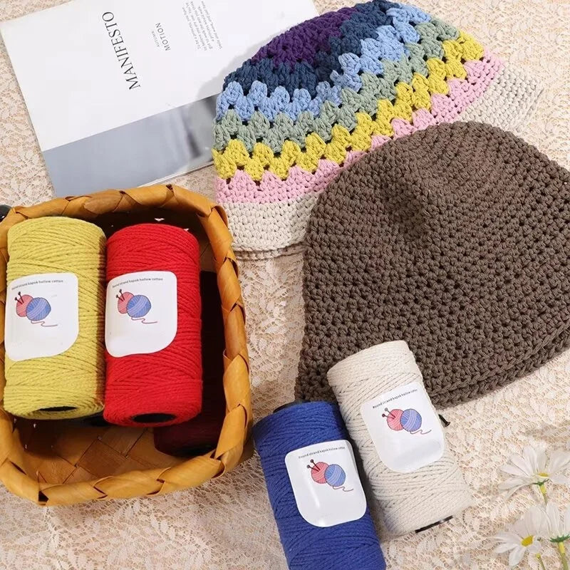 A collection of hand-woven cotton yarn in various colors and textures, including a knitted hat and several skeins.